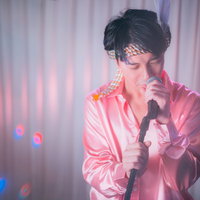 ピンクのステージ衣装で熱唱する男性アイドルの写真