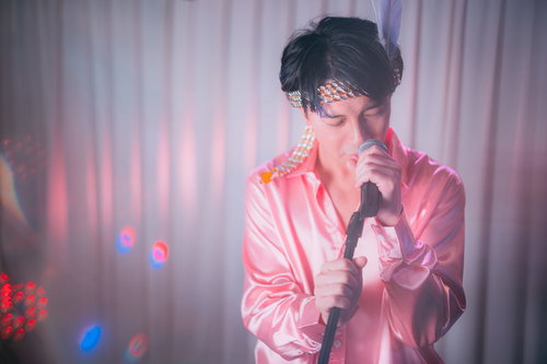 ピンクのステージ衣装で熱唱する男性アイドル