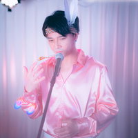 ピンクのシャツでマイクを握りステージで熱唱する男性アイドルの写真