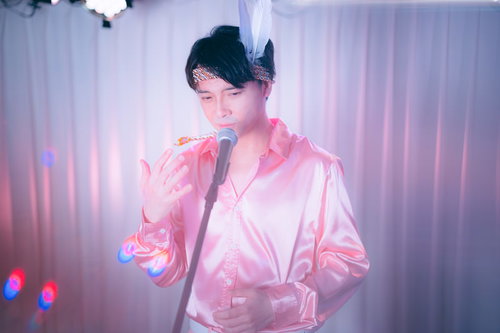 ピンクのシャツでマイクを握りステージで熱唱する男性アイドル