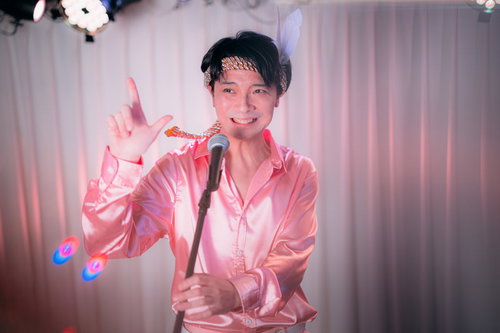 ピンクのシャツでマイクを握り熱唱するアイドル志願の男性