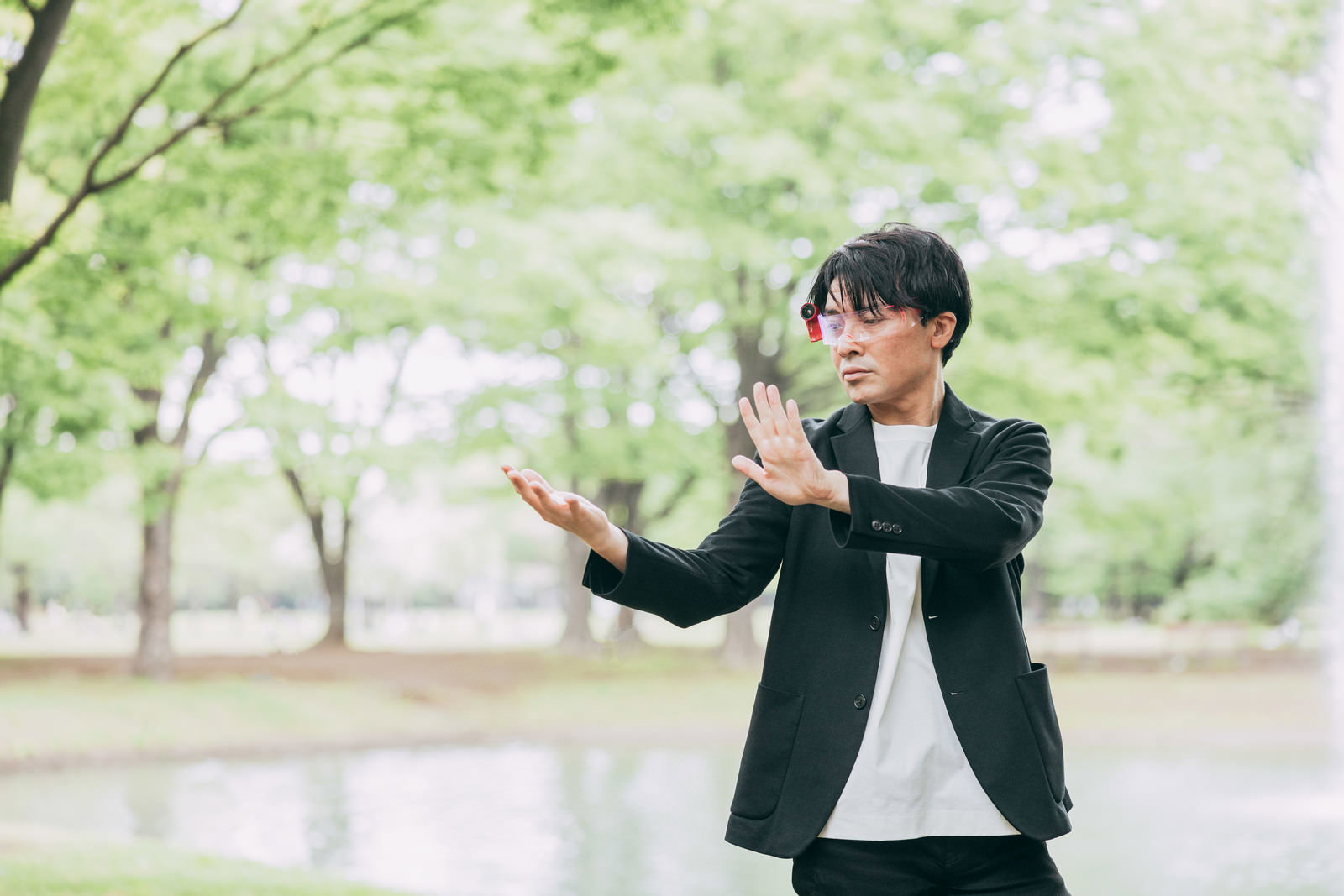 公園で両手を広げるポーズの男性［モデル：金子周平］