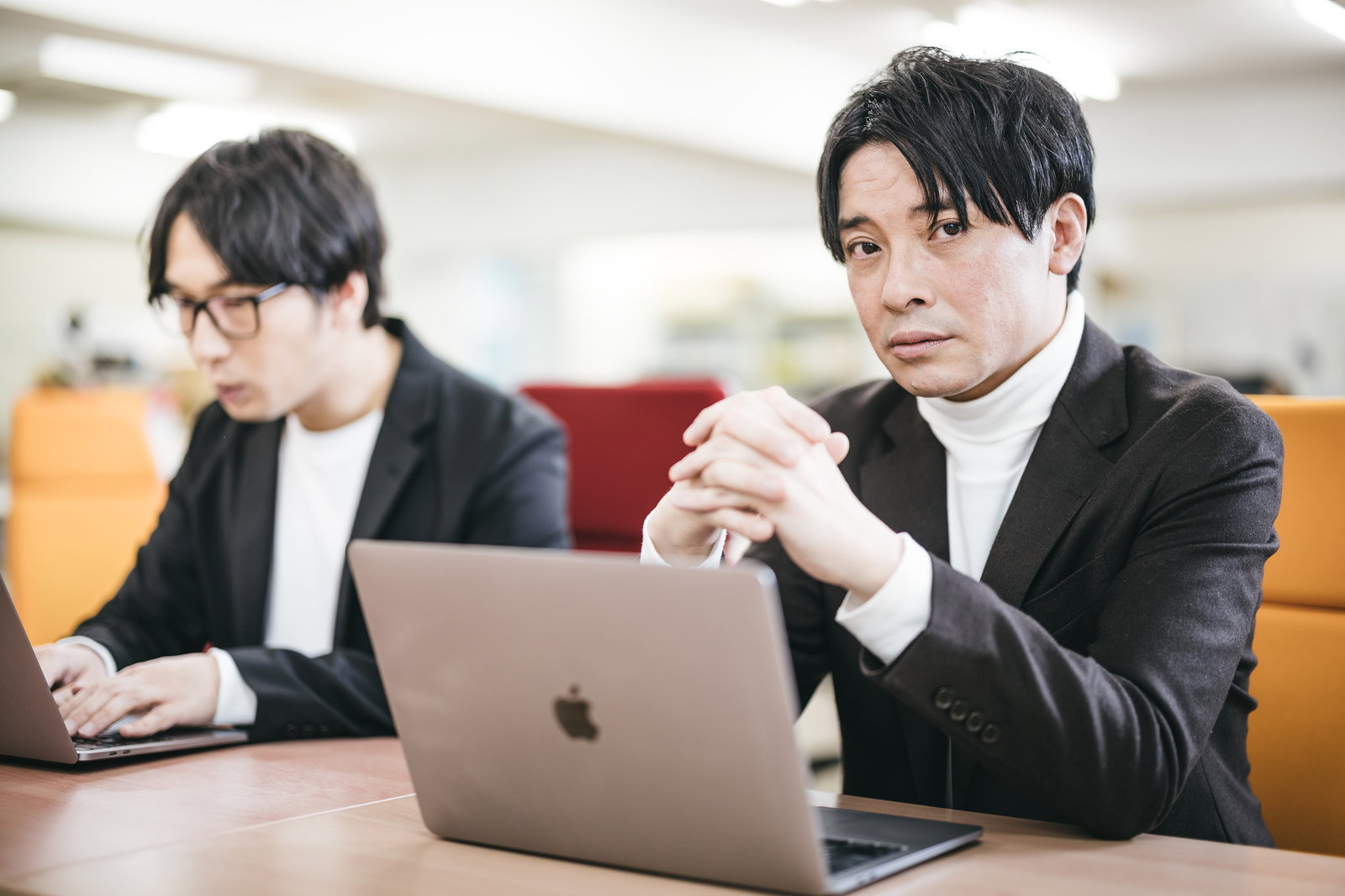 ノートパソコンを確認しながら説明するビジネスマンと若い男性スタッフ［モデル：大川竜弥 金子周平］