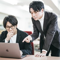 部下の失態をパソコン画面で指摘する上司の厳しい表情の写真