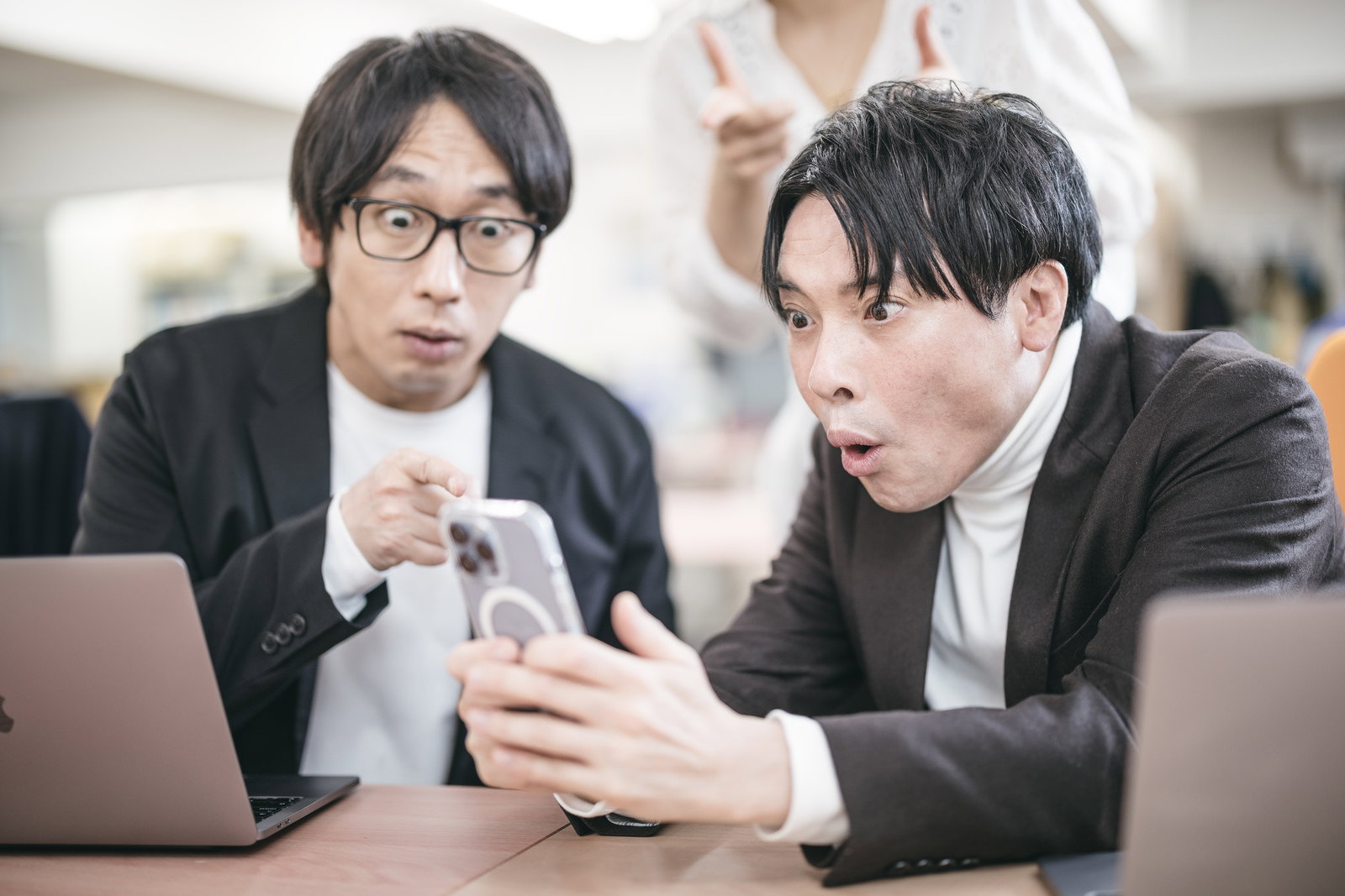 スマートフォンを見て驚く男性エンジニアと同僚［モデル：金子周平 大川竜弥］