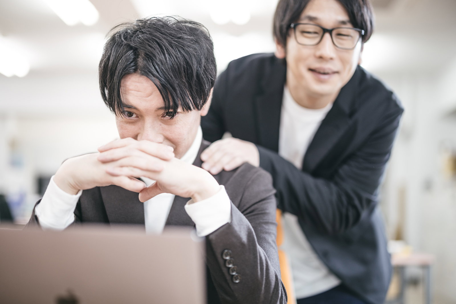 上司に肩をたたかれ顔色を伺うスーツ姿の男性社員［モデル：金子周平 大川竜弥］