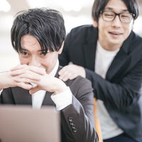 上司の肩を揉んで顔色を伺うリストラ候補の男性社員の写真