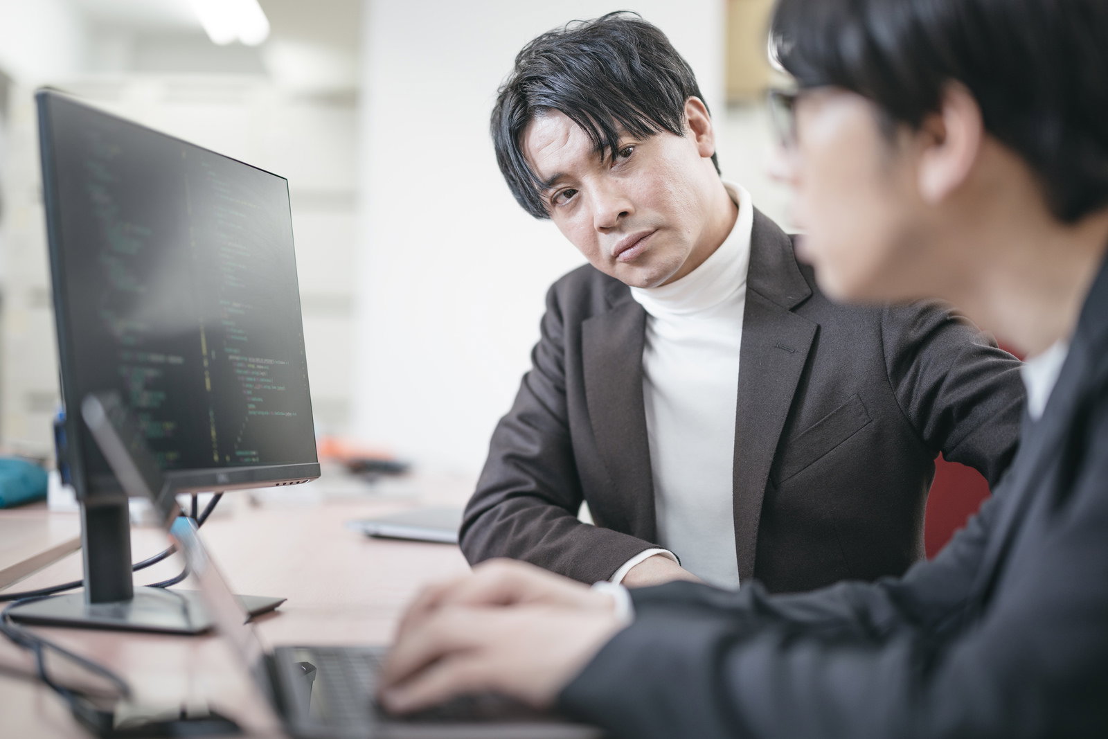 会議中にエンジニアの説明を聞くIT企業の社長［モデル：大川竜弥 金子周平］