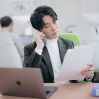書類を確認しながら電話で部下に指示を出す経営者の写真