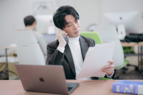 書類を確認しながら電話で部下に指示を出す経営者
