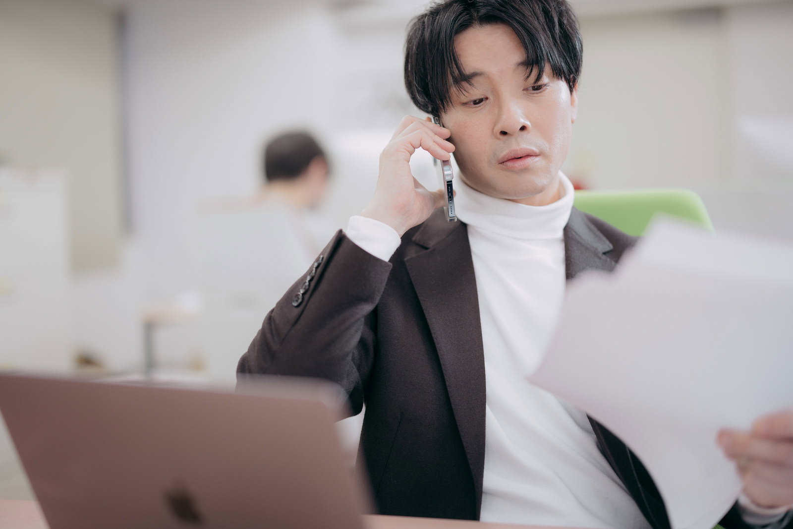スーツ姿の男性がタブレットを持ちながらスマートフォンで電話する［モデル：金子周平］