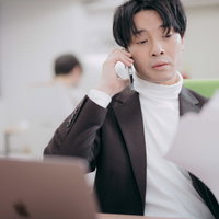 報告書の問題に気づいて関係者に電話するプロデューサー男性の写真