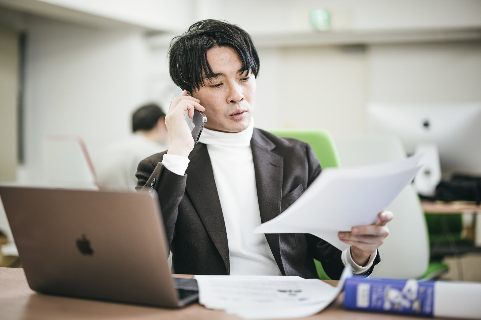 電話で書類を確認しながら指示を出す男性ビジネスマン［モデル：金子周平］