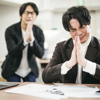 運頼みの入札案件で祈願する男性ビジネスパーソンの写真