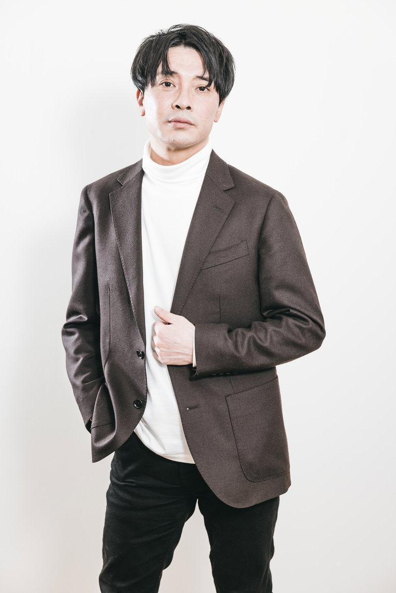 茶色のジャケットと白いタートルネックを着た会社役員の男性［モデル：金子周平］