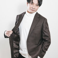 茶色のジャケットを着た社長の宣材撮り、白いタートルネック合わせの写真