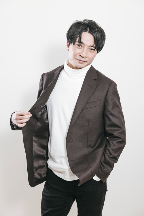 茶色のジャケットを着た社長の宣材撮り、白いタートルネック合わせ