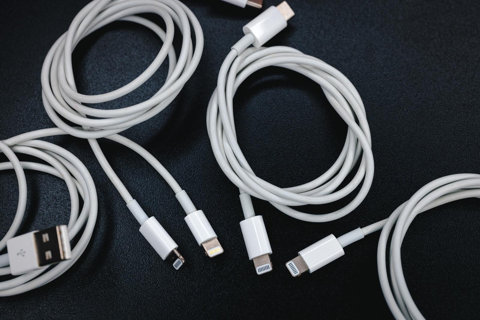 黒い布の上に置かれた白いLightningケーブルと充電ケーブル複数本