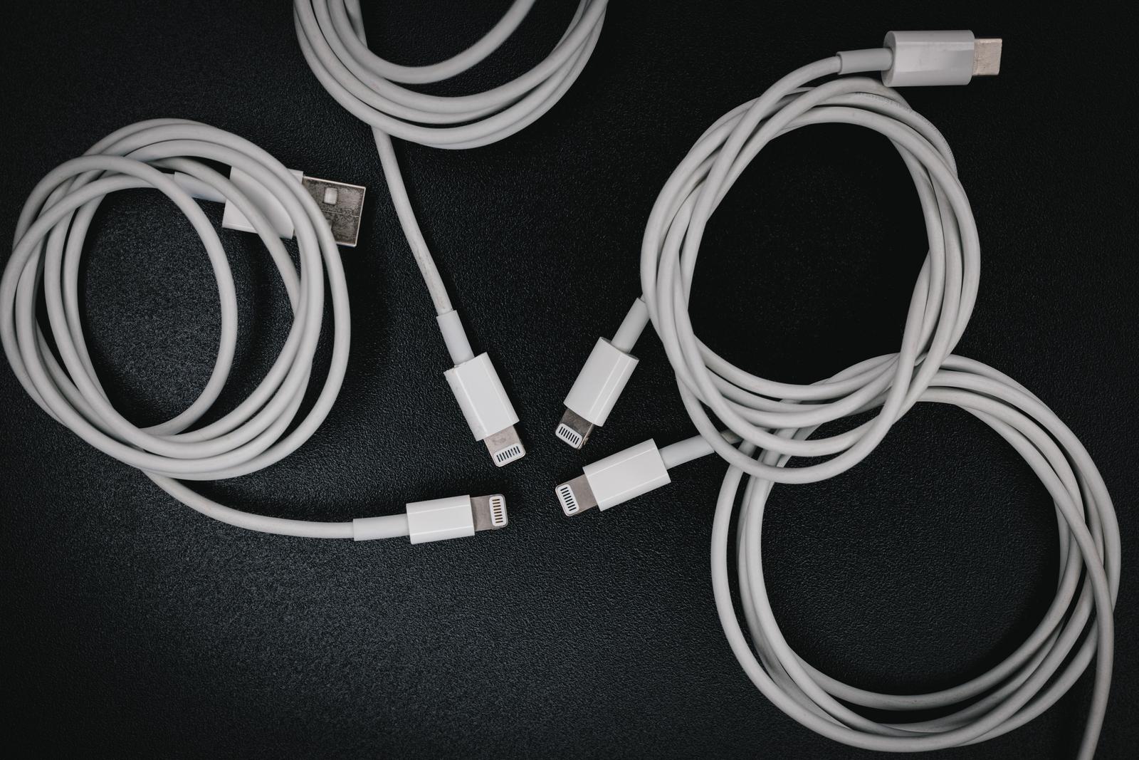 4本の白いライトニングケーブルとUSB-Cケーブルが黒い布の上に配置された写真