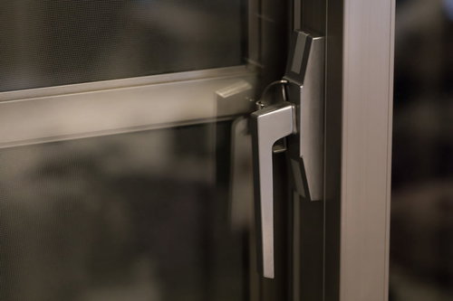 白い窓枠のクレセント錠を締める手