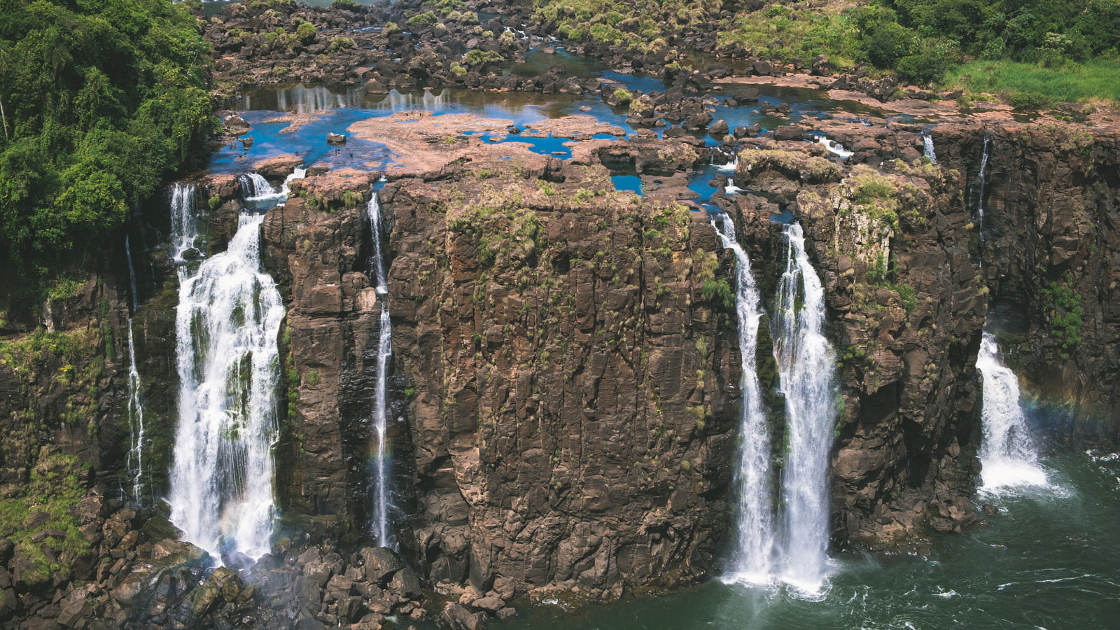 切り立った岩壁から複数の滝が流れ落ちるイグアスの滝の光景