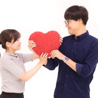 赤いハートをがっちり握るカップルの愛情表現の写真