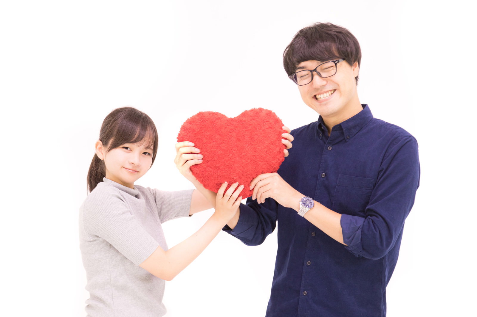 赤いハートを一緒に持って笑顔で見つめ合うカップルの男女［モデル：真崎真幸 千歳］