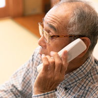 受話器を耳に当てて電話中のお爺さんの写真