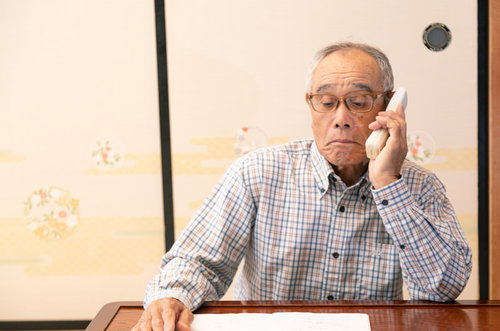老人会の名簿をチェックしながら電話をかける爺さん