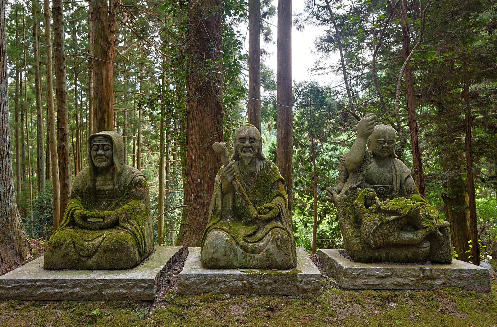 森の杉林に囲まれた、苔むした三体の石仏が並んで鎮座している