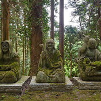 森の中に佇む東堂山満福寺の苔むした三体の石仏像の写真