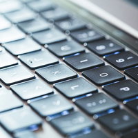 グレーのMacbookキーボードを斜めから捉えたの写真