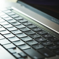 光が反射するMacBookのキーボード、黒いキーが規則正しく配列の写真