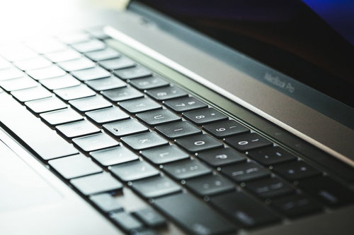 光が反射するMacBookのキーボード、黒いキーが規則正しく配列