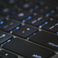 ライトがついたMacBookのリターンキーの写真
