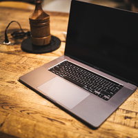 木製テーブルの上に置かれたMacbookとガベルの写真