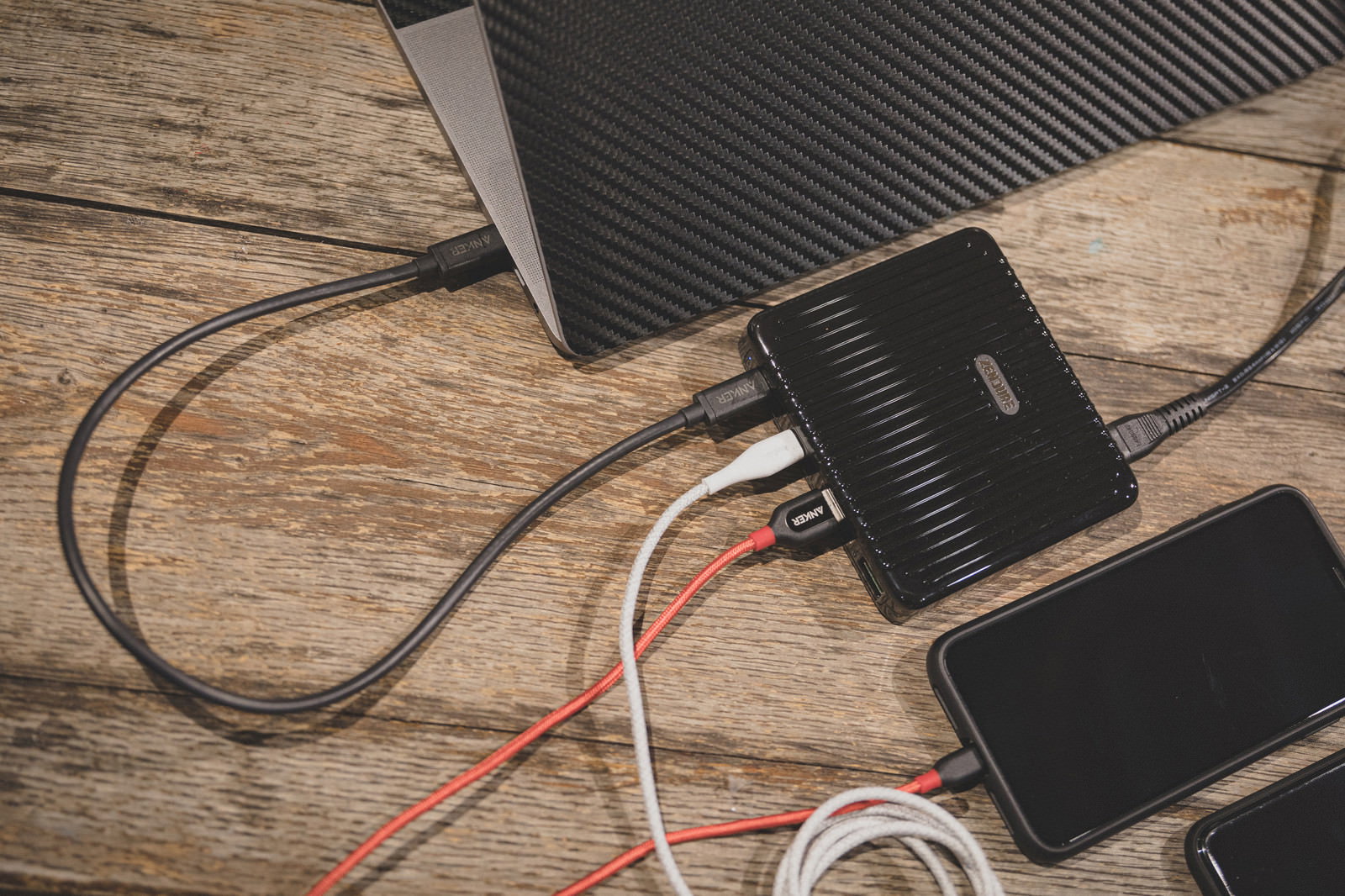 木目のデスクでモバイルバッテリーから複数のケーブルでスマホを充電