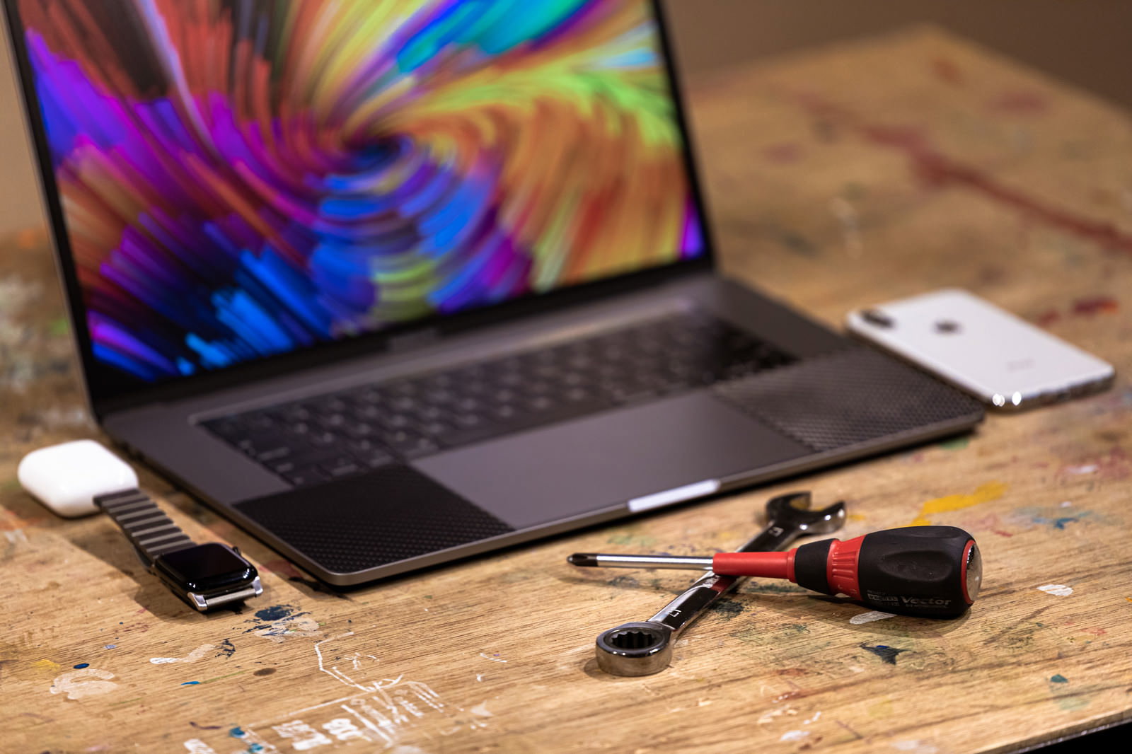 作業台の上に置かれたMacBookとApple製品と工具