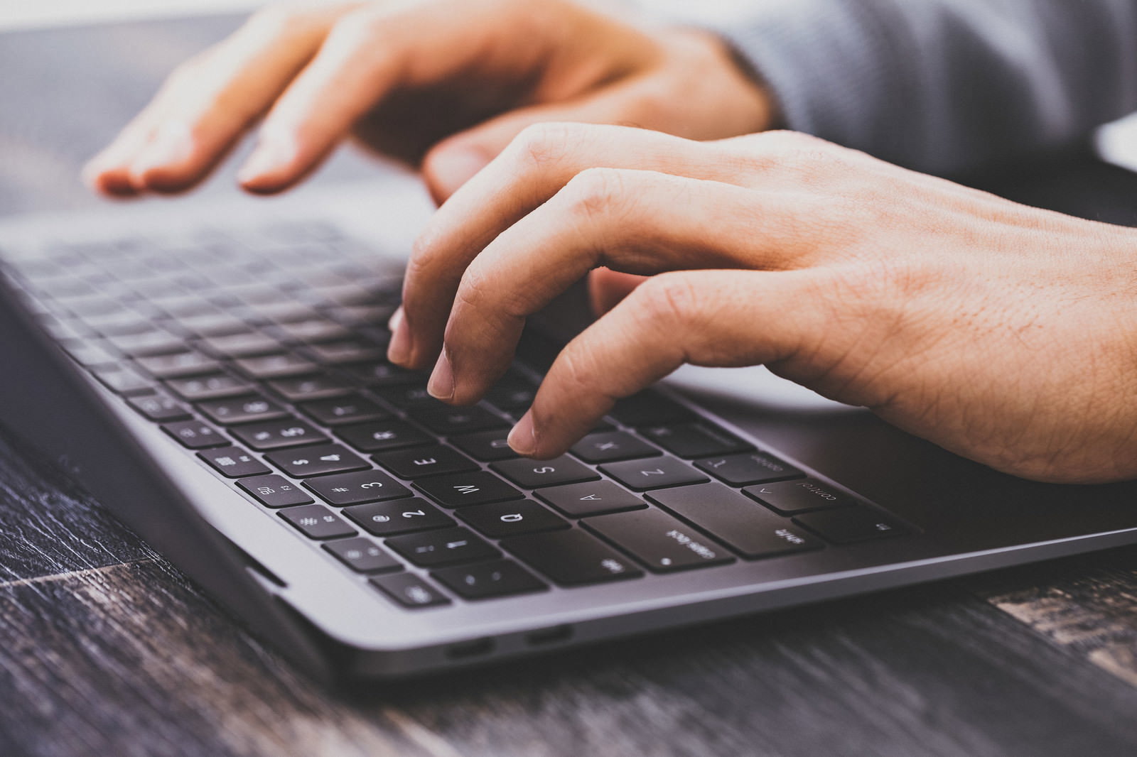Macbookのキーボードをタイピングする人物の手元