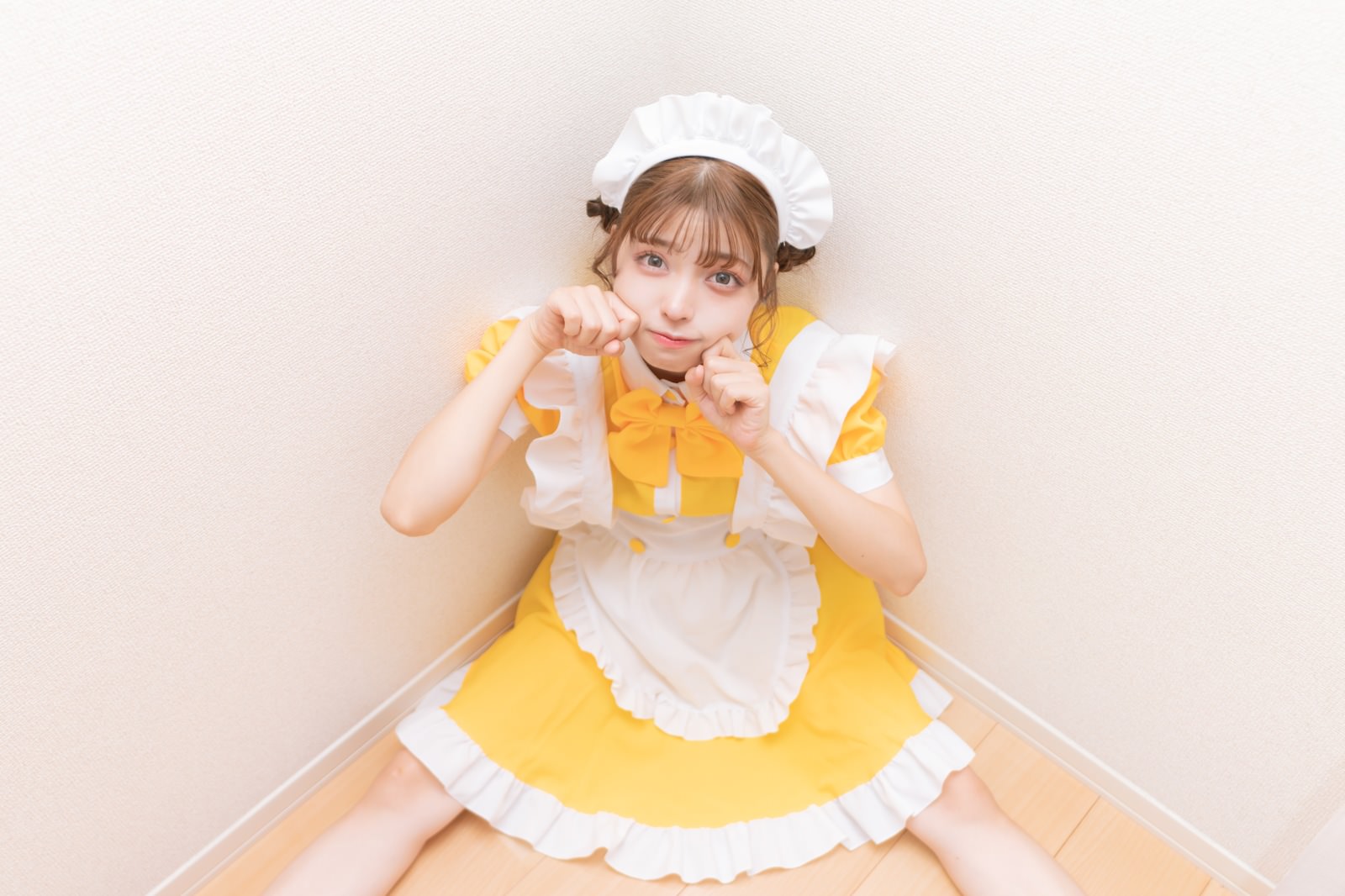 黄色いメイド服と白いエプロンを着て笑顔で座る女性［モデル：高尾実生］