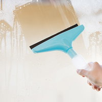 青色の水切りワイパーで窓掃除をする手元の作業風景の写真