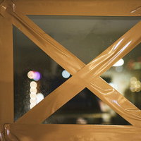 窓ガラスにテープを✕に貼って割れないようにする応急処置の写真