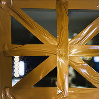 窓ガラスに黄色いガムテープで強風対策を施しましたの写真