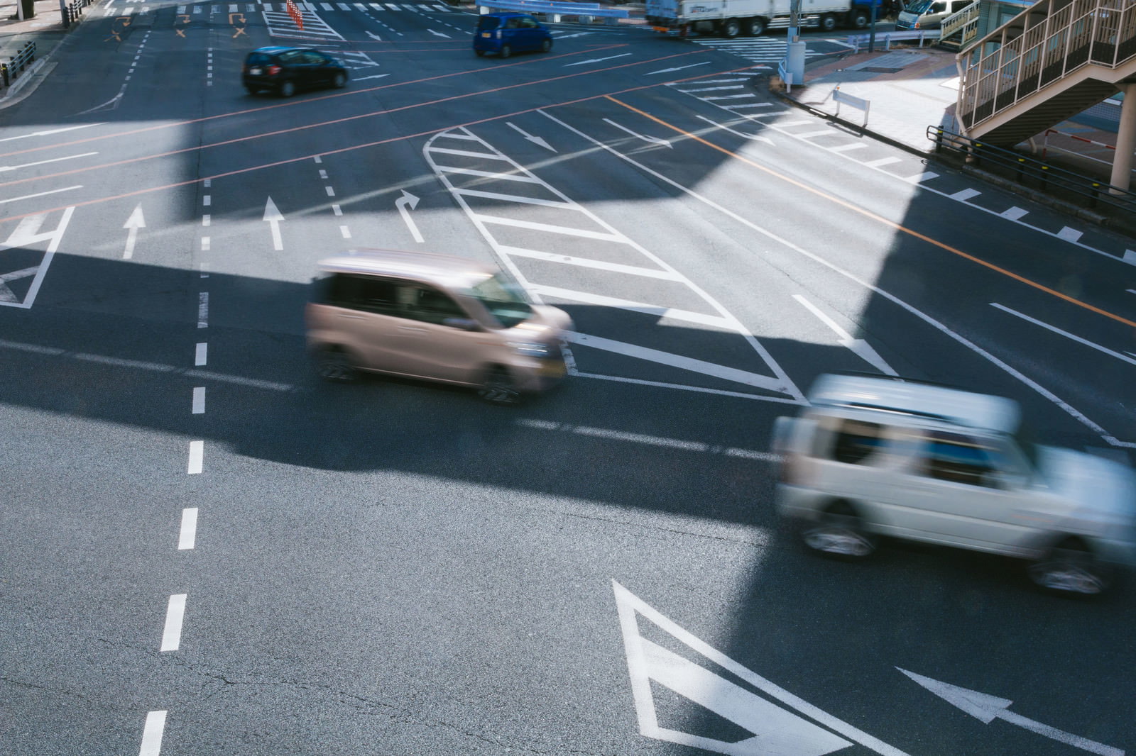 複数の車線と白い矢印が描かれた道路交差点を車が通行している