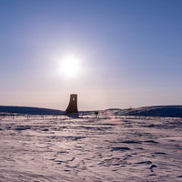 冬の雪原に聳え立つ赤い避難塔の写真