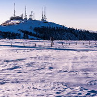 山頂に立つ雪化粧した電波塔の写真