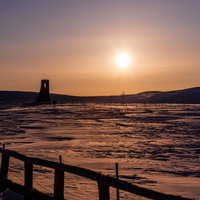夕暮れの雪原に立つ避難塔のシルエットの写真