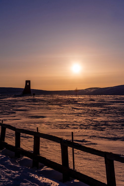 夕暮れの雪原に立つ避難塔のシルエット・冬景色
