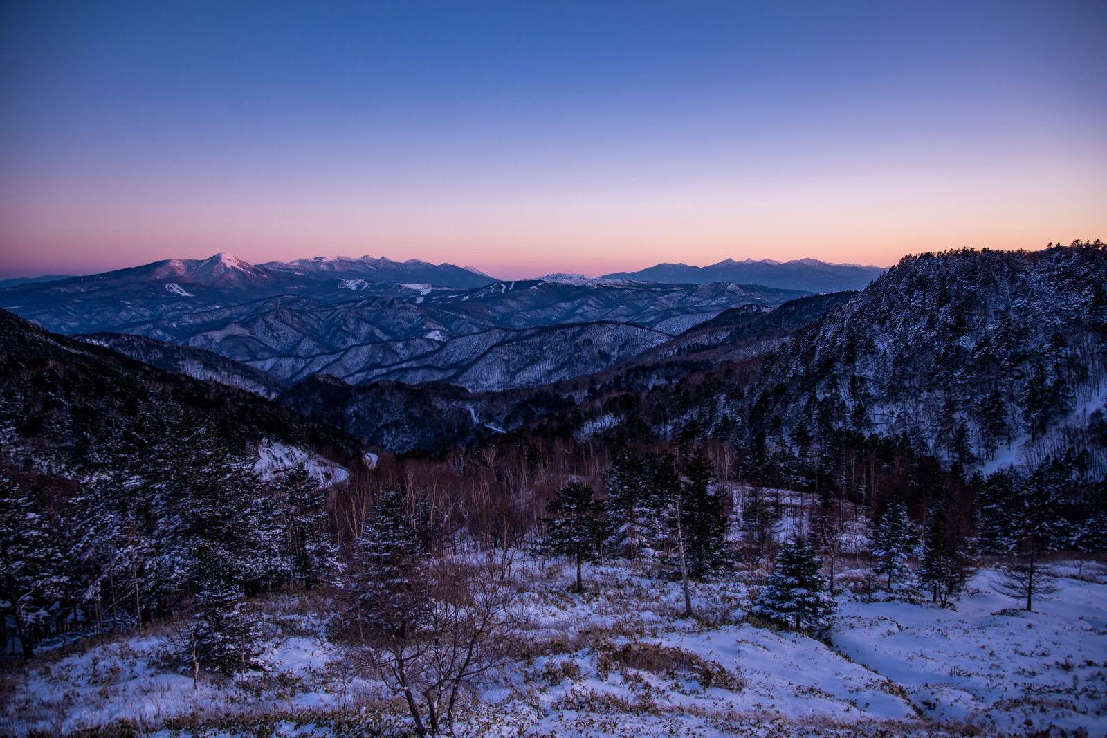 夕焼けに染まる空と雪化粧した山々の冬景色