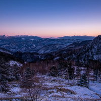 焼けた空と雪化粧の雪山が連なる冬景色の写真